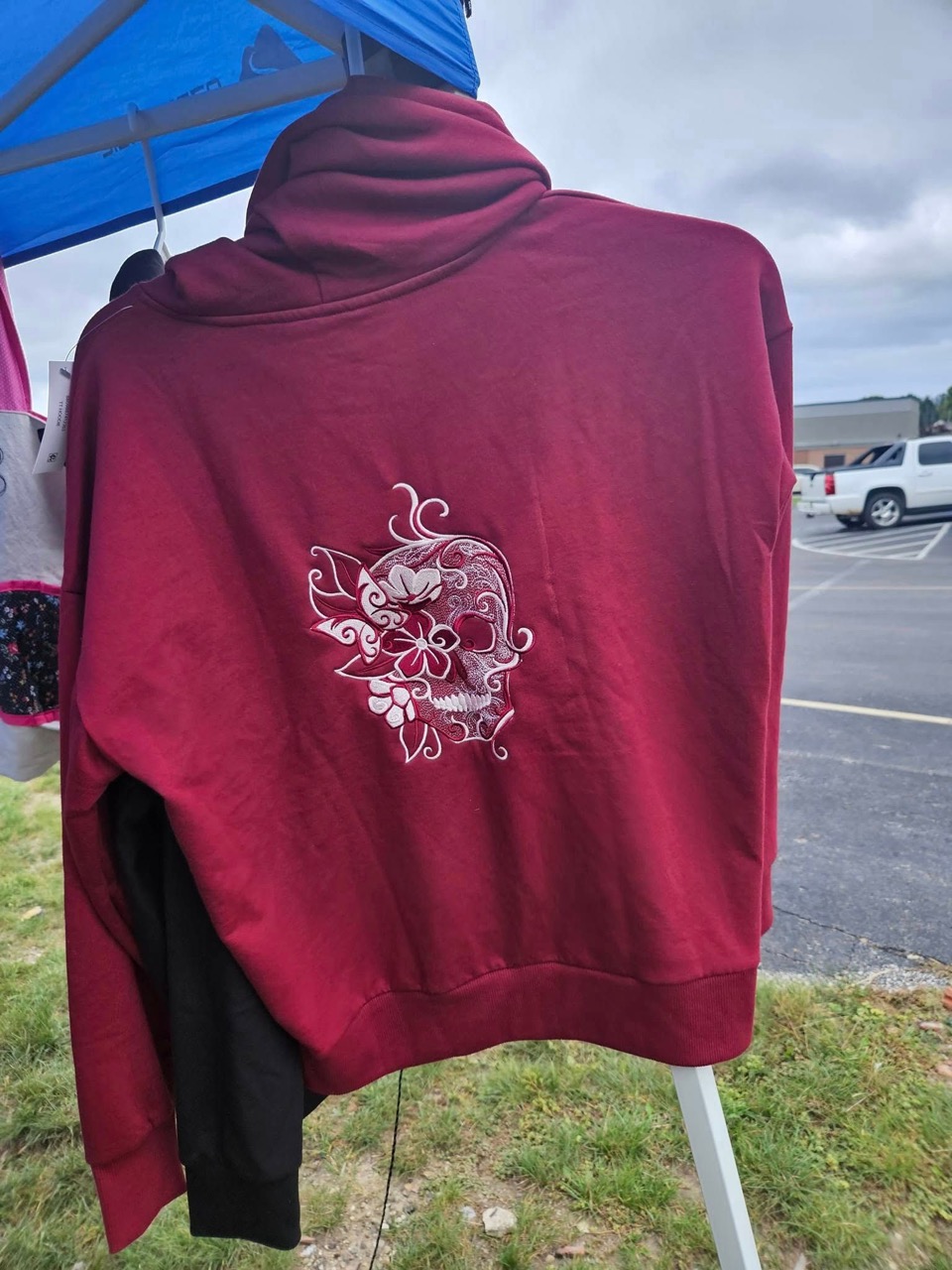 Burgundy hoodie with a pink sugar-skull and floral embroidery on the back