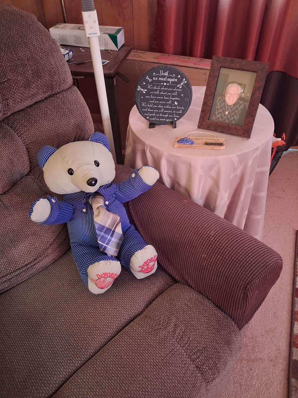 Memory keepsake bear sewn from blue striped pajamas, displayed beside a loved one's memorial photo