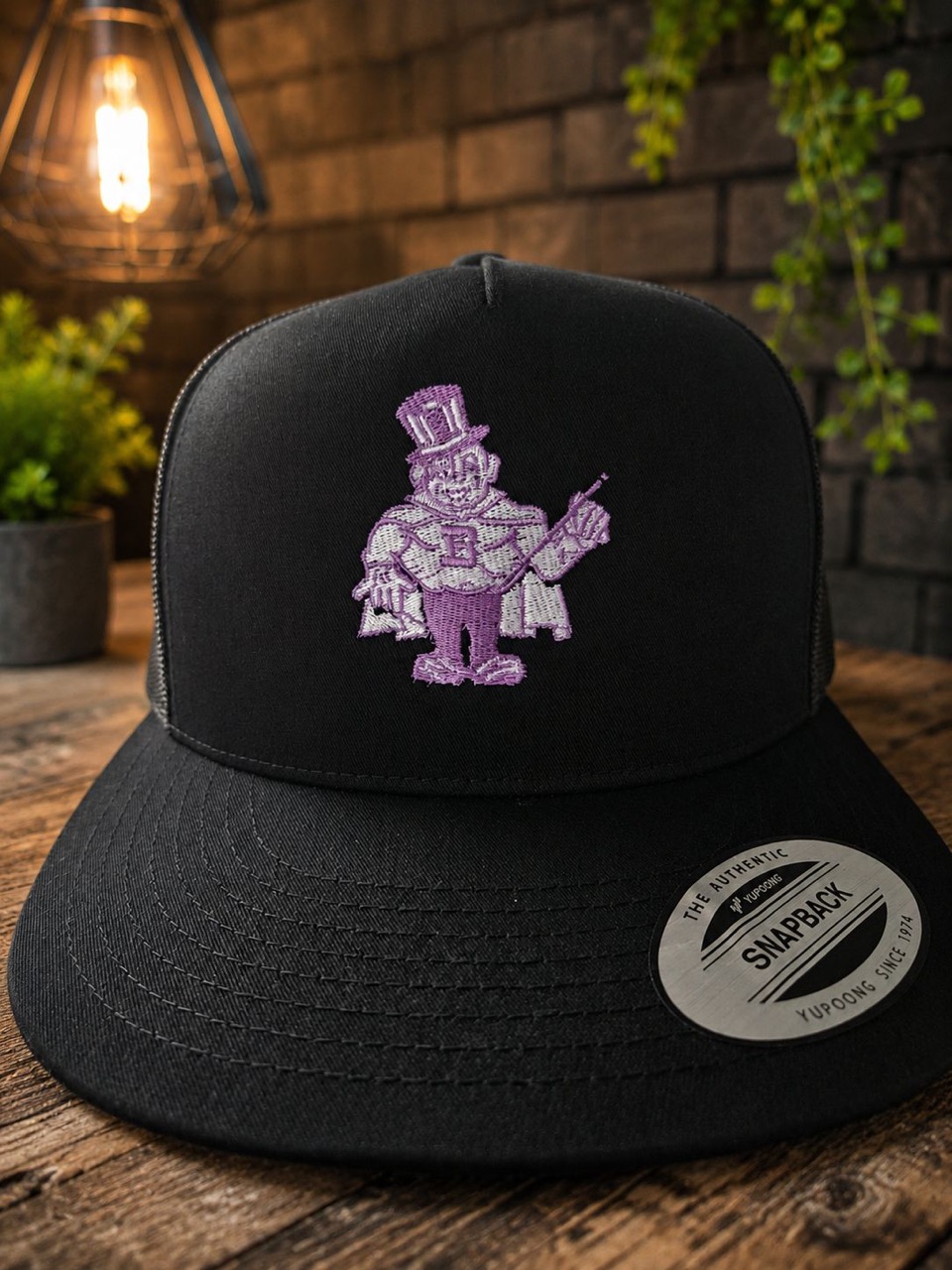 Black snapback cap embroidered with the purple Barberton Magics top-hat magician mascot
